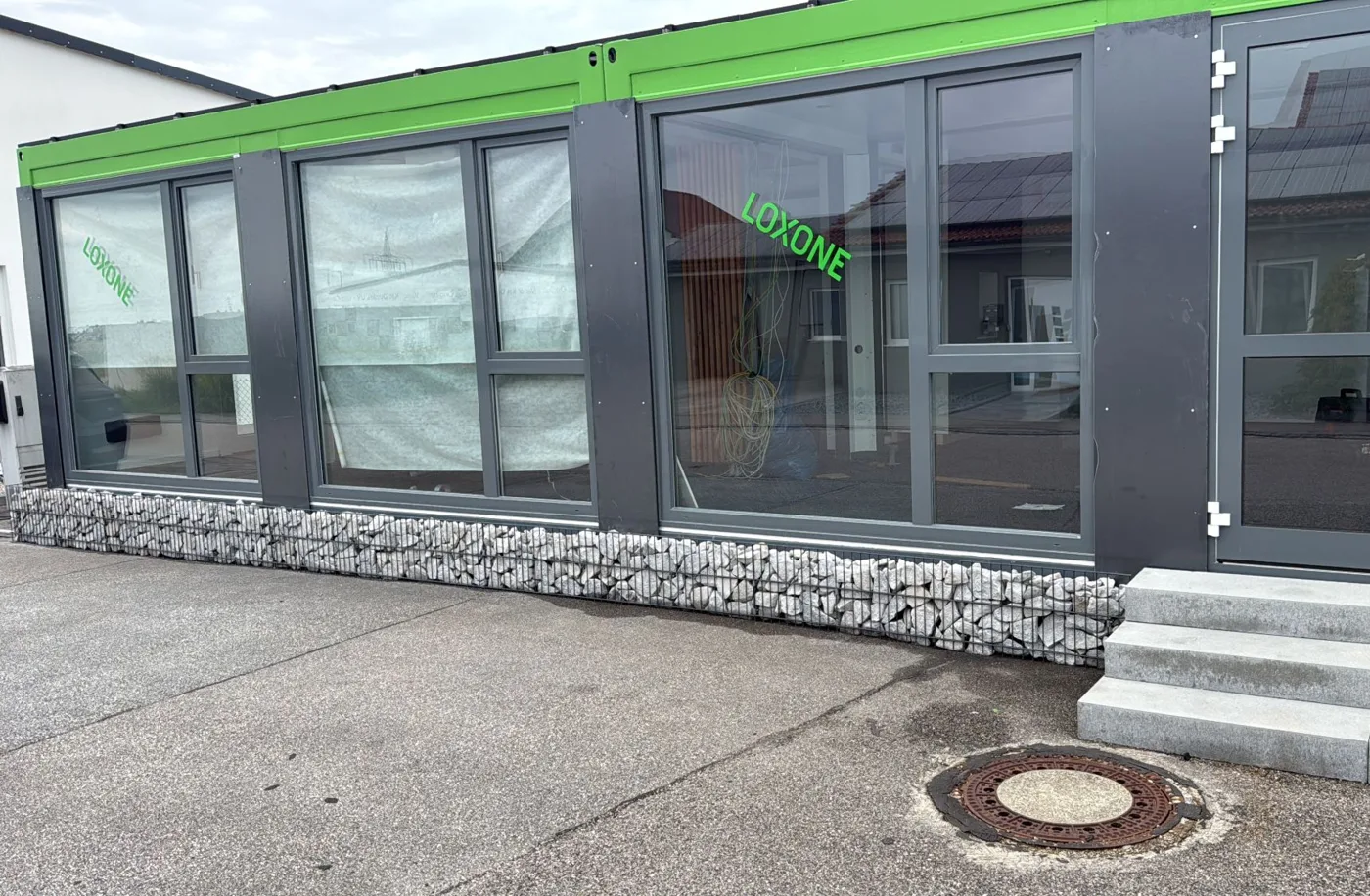 Showroom-Front mit Loxone-Beschriftung, Gabionen und Granitstufen