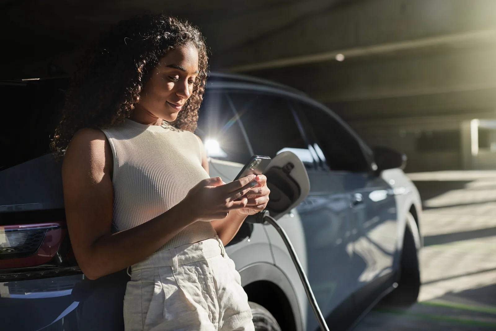 Frau lädt E-Auto mit App